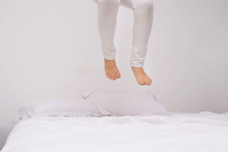 How high can you go. the legs of a little girl jumping on the bed.
