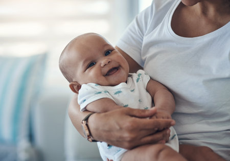 A babys laugh is best of all. a young woman carrying her adorable baby girl at home.の写真素材