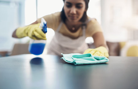 An invisible shield against viruses and bacteria. a young woman disinfecting a table at home.の写真素材