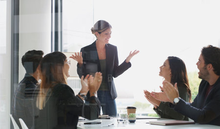 They look up to her as an inspiring leader. a group of businesspeople applauding during a meeting in a boardroom.の写真素材