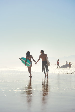Were ready to surf on. a young couple spending the day at the beach with their surfboards.の写真素材