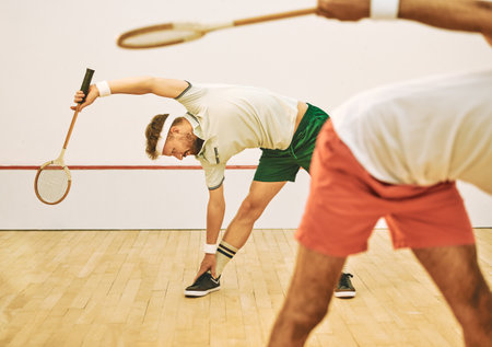 A pre game warmup is a must. two young men stretching before playing a game of squash.の写真素材