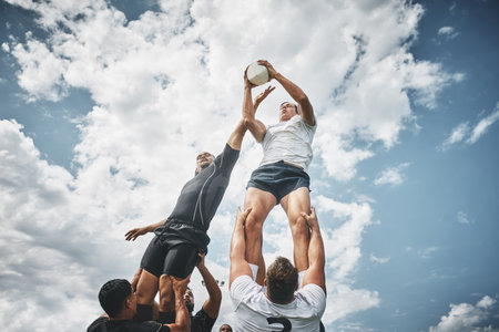 Got you. Low angle shot of two rugby teams competing over a ball during a line out of a rugby match outside on a filed.の写真素材
