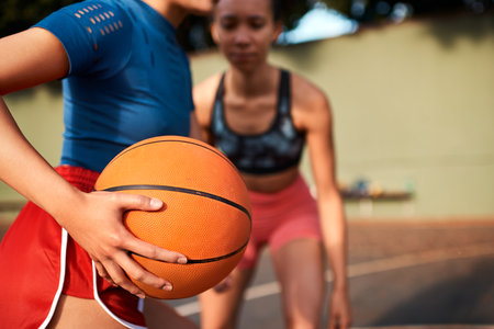 Protecting the ball from my opponent. an unrecognizable sportswoman holding the basketball away from her opponent during the game.の写真素材