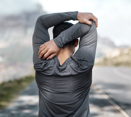 Only look forward, never behind. an unrecognizable man stretching before exercising outdoors alone.の写真素材