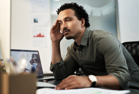 Come on, think. a handsome young businessman sitting alone in the office and feeling stressed while...