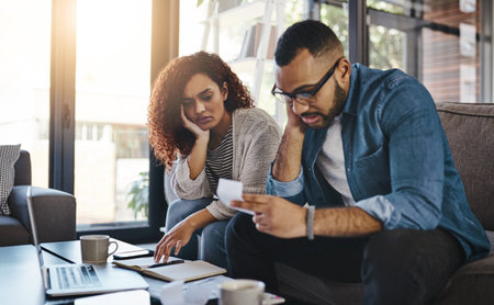 Is this really the state of our expenses. a young couple looking stressed out while working on their budget at home.の写真素材