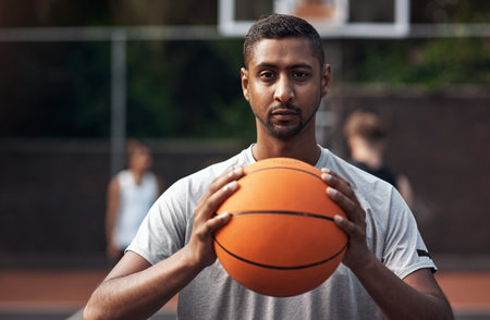 Its game time. Portrait of a sporty young man standing on a basketball court.の写真素材