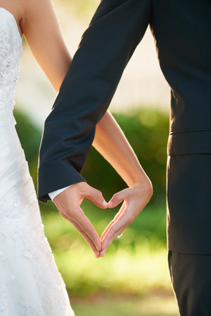 Hands, bride and groom heart sign at wedding, celebration or vow ceremony and love, couple and marriage. Man, wife and commitment together and care, unity and promise for relationship happinessの写真素材