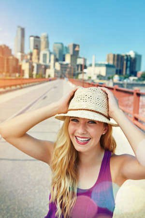 The city is the place to be. a smiling young woman walking around the city in the summertime.の写真素材