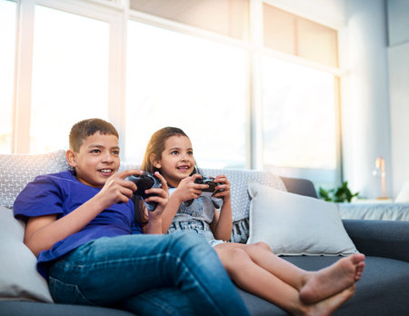 Were always competitive when we play against each other. two young children sitting on a sofa and...