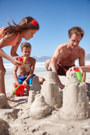 Their favorite form of beach fun. a happy family building sandcastles together at the beach.の写真素材