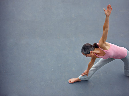 Keeping her mind and body sharp with yoga. a mature woman doing the extended triangle yoga pose outdoors.の写真素材