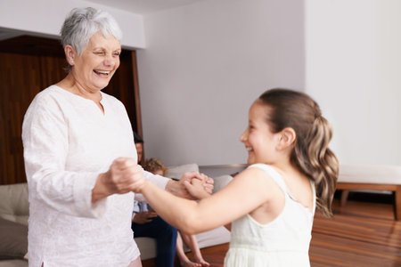 Holding hands, dance or happy grandmother with a child playing or laughing with joy in family home. Grandma dancing, kid smiling or funny old woman relaxing or bonding together in retirement or houseの写真素材