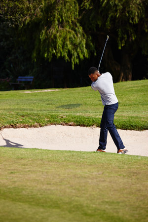 Aiming for the green. a handsome young man playing a game of golf.の写真素材