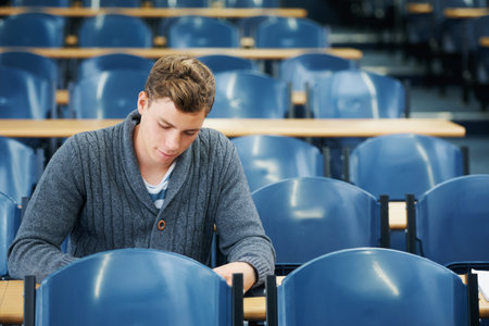 The last student in the lecture hall. A young man sitting alone in a lecture hall.