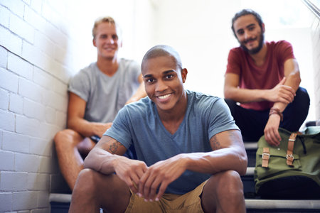 Chilling with the boys before class. male university students sitting together on the steps of a stairwell.の写真素材