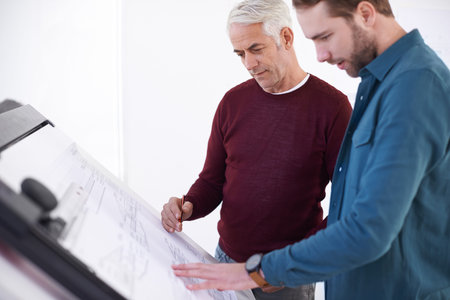 How can we open this up a bit. two male architects working on a building plan at a drawing board.