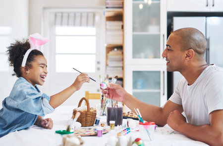Dad, youve always been the coolest. a man painting eggs with his daughter at home.の写真素材