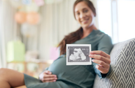 My little one is growing fast. a young mother to be holding an ultrasound of her unborn child.の写真素材