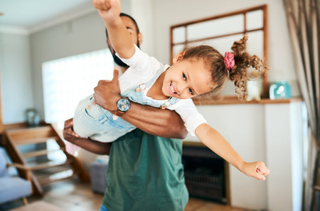 With dads love, she can soar through the world. a father and his little daughter having fun together at home.の写真素材