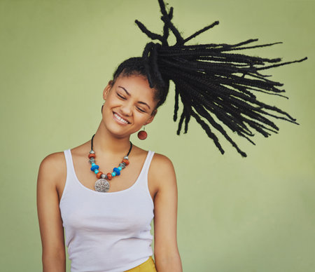Life is short, make every hair flip fabulous. an attractive young woman tossing her hair against a green background.の写真素材