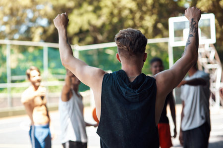 Talent wins games, teamwork wins championships. Rearview shot of a sporty young man cheering with his friends on a sports court.の写真素材