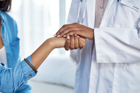 This is a safe space. a doctor holding hands with a patient in her consulting room.の写真素材