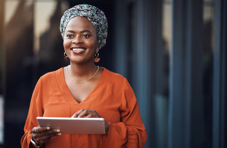 Its the future of business. an attractive businesswoman using her tablet while standing in the office.の写真素材