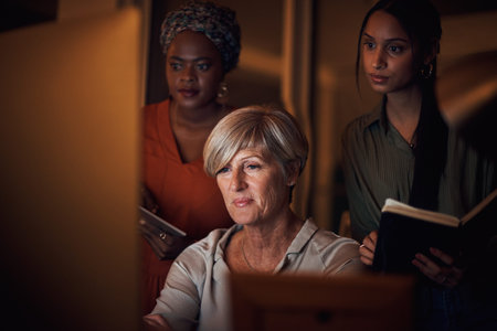 Well get the deadline done tonight. a group of businesswomen working together on a computer in an...