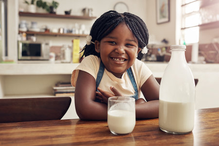 Cookies are the only thing thats missing now. Portrait of an adorable little girl drinking milk in the kitchen at home.の写真素材