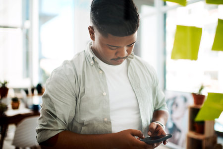 Brainstorming sessions just got smarter. a young businessman using a smartphone while having a brainstorming session in a modern office.の写真素材