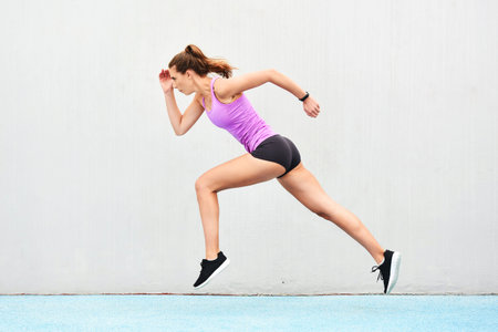 Hitting top speed. Full length shot of an attractive young female athlete running along the track.の写真素材