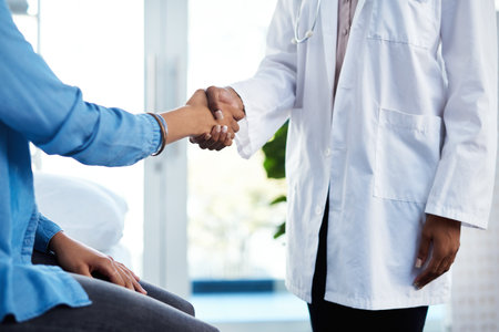 Nice to meet you doc. a doctor shaking hands with a patient in her consulting room.の写真素材