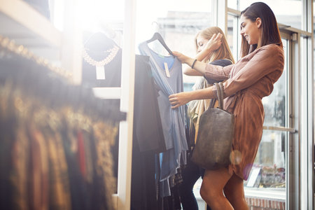 I can wear this with everything I own. a young woman holding up an item that she picked out in a clothing store.の写真素材