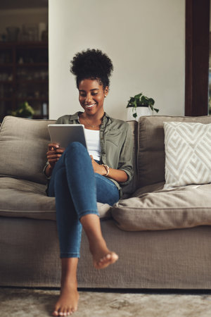 Enjoying my own company. Full length shot of a beautiful young woman using a digital tablet while...