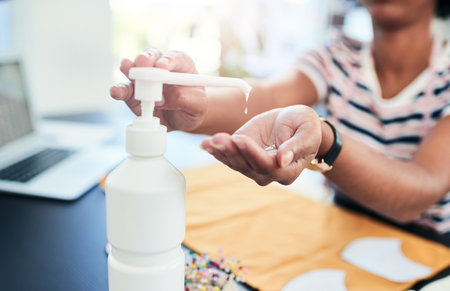 You can expect professionalism from my home business. a young designer using hand sanitiser while working at home.の写真素材