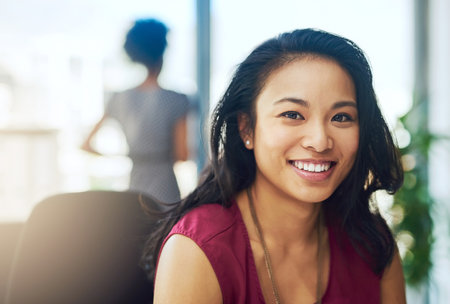 Backed by motivation and ambition. Portrait of a young businesswoman sitting in a modern office.の写真素材