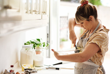 I love baking more than anything else in the world. a young woman mixing batter in a glass bowl.の写真素材