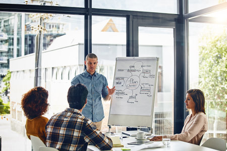 His presentation will surely inspire them to succeed. a businessman giving a presentation to coworkers in a boardroom meeting.の写真素材