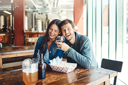 We go together like Friday and happy hour. a happy young man and woman having beers at a bar.の写真素材