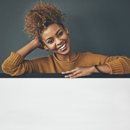 Its a message I firmly believe in. Studio portrait of a young woman standing behind a blank sign against a grey background.