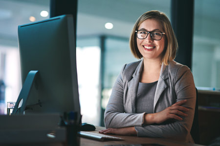 Fulfilling her ambitious dreams throughout the day and night. Portrait of a young businesswoman working late in an office.の写真素材