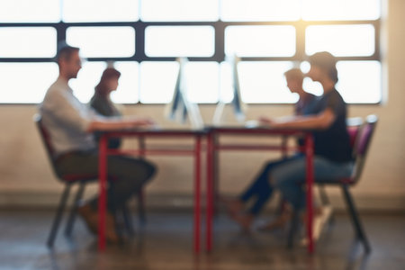 They only thing theyre focused on is success. Blurred shot of a group of designers working on computers in an office.の写真素材