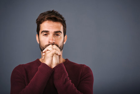 Putting the power of prayer to the test. Studio shot of a handsome young man praying against a gray background.の写真素材