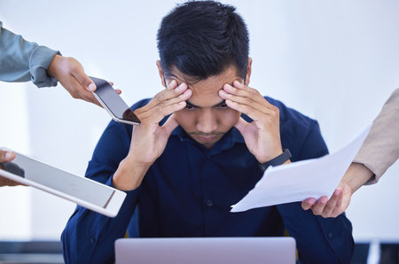 The challenges of work. a young businessman looking stressed out while working in a demanding office environment.の写真素材