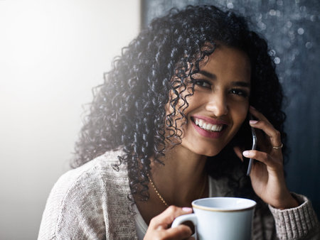 I think I have to call my mom for a change. a cheerful young woman relaxing and drinking coffee...