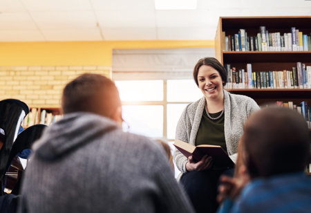 Theyre always looking forward to story time. an elementary schoolteacher reading a book to her...