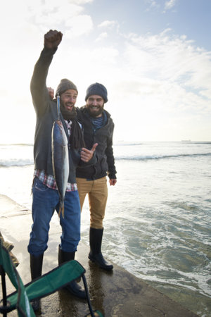 My biggest catch yet. two young men fishing at the ocean.の写真素材