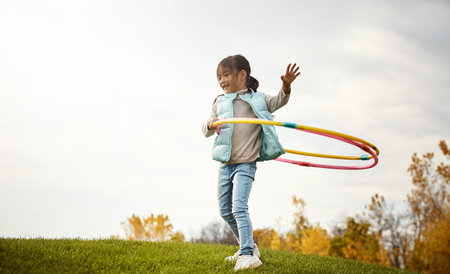 Enjoying some hula hooping fun. an adorable little girl spending the day outdoors.の写真素材